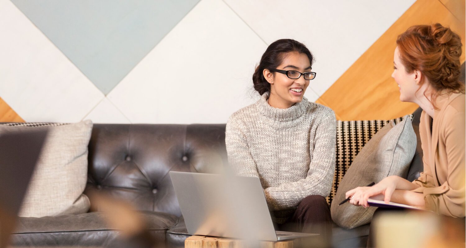 Two young women talk about business.
