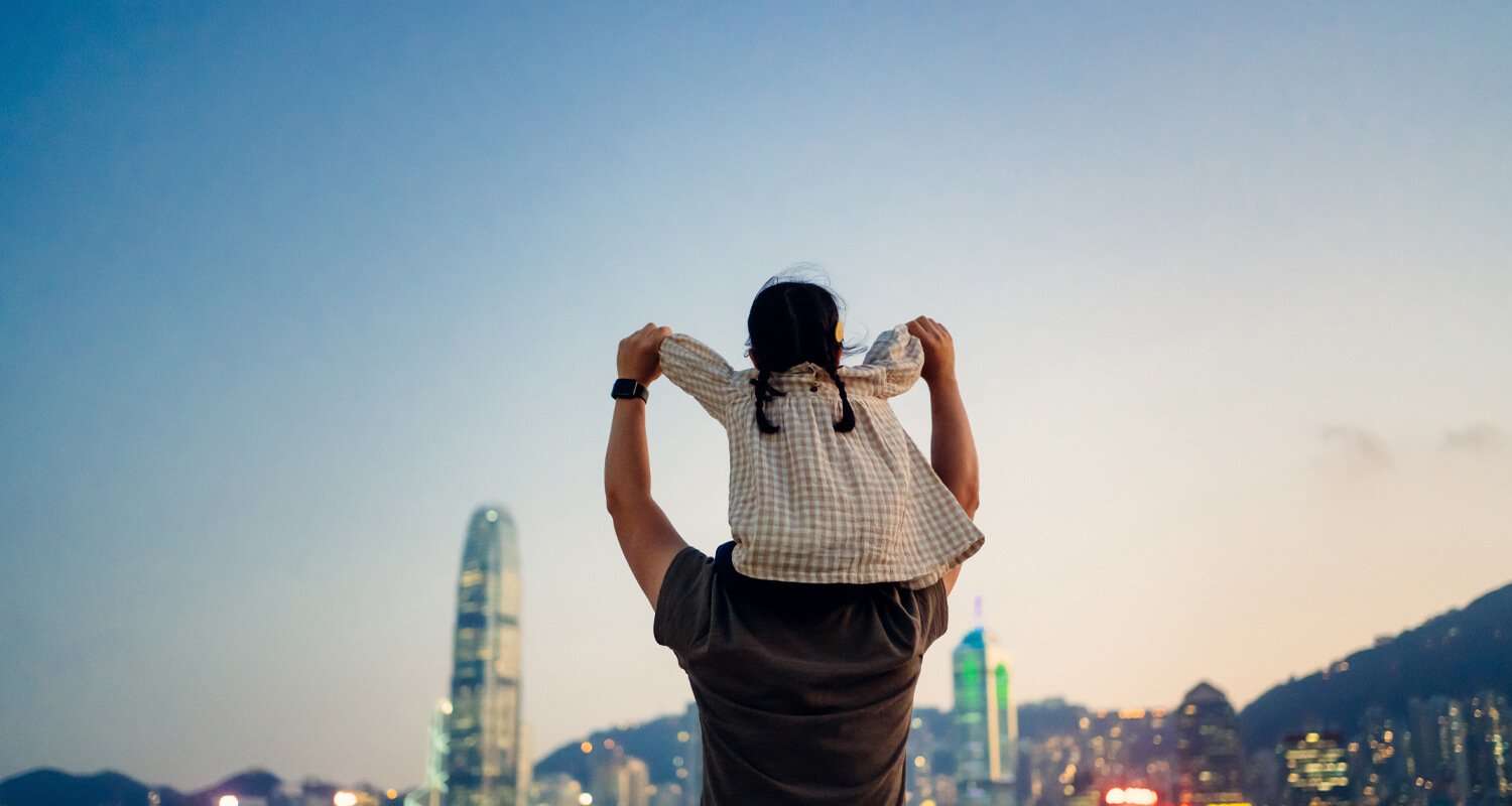 Child sitting on dads back looks at the skyline.